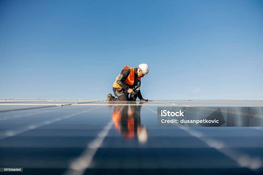 A handyman on the rooftop installing solar panels.